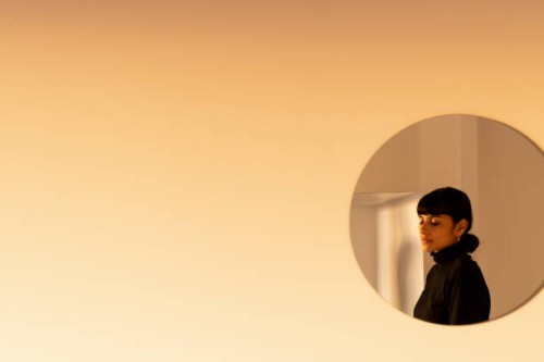 reflection of a young woman on a round mirror by the wall - fashion stock pictures, royalty-free photos & images