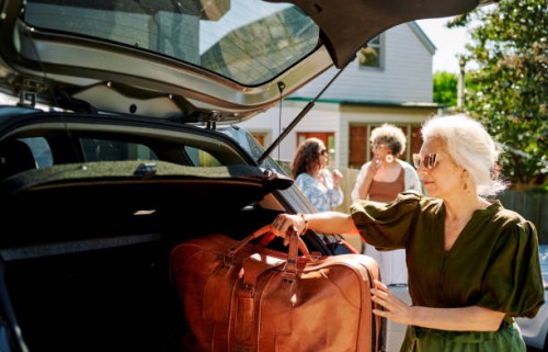 reife frau packt gepäck in ein auto für einen roadtrip mit freunden - travel stock-fotos und bilder