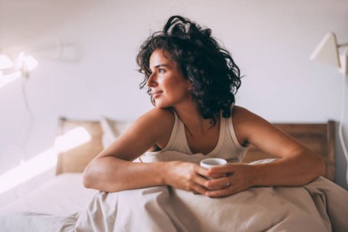 relaxed woman enjoying morning coffee in cozy bedroom - coffee stockfoto's en -beelden