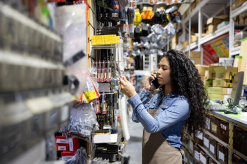 retail clerk working at a hardware store and talking on the phone while searching for a product - home decoration stock pictures, royalty-free photos & images