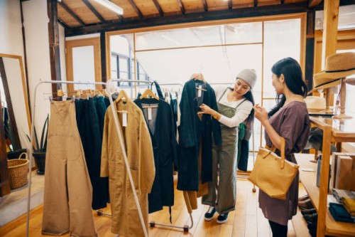 retail shop clerk helping a mid adult woman customer shop for clothing in a boutique - fashion stock pictures, royalty-free photos & images