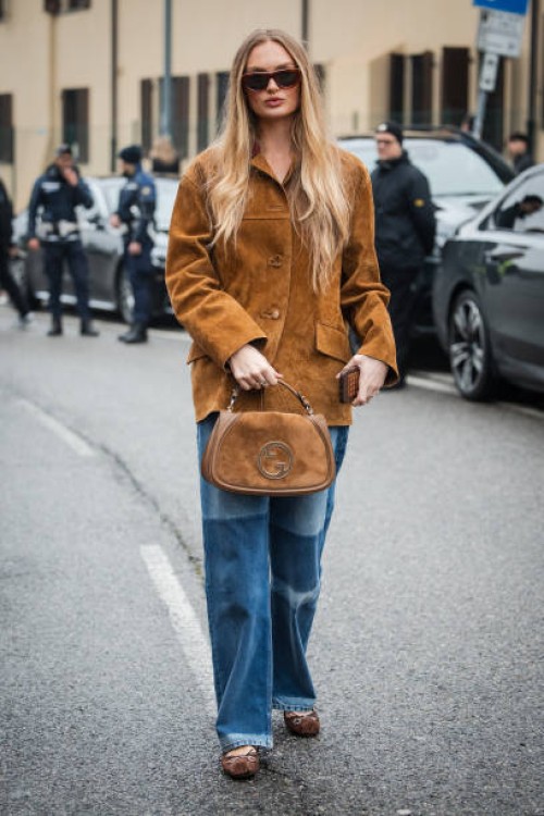 Romee Strijd is seen wearing a brown leather jacket, blue denim pants, sunglasses and brown suede Gucci Blondie bag outside Gucci during the Milan...