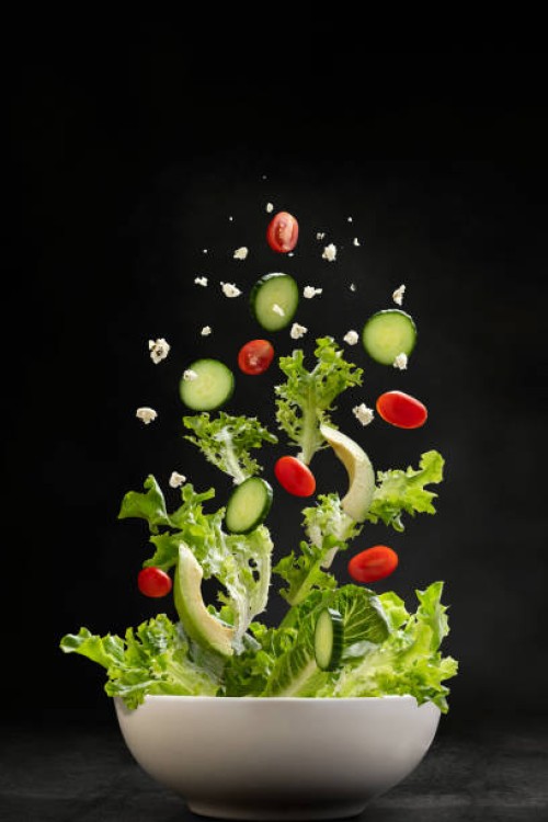 salad ingredients flying through the air, landing in a bowl - food stock pictures, royalty-free photos & images