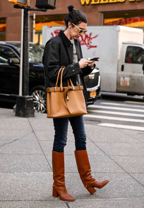 Sally Holmes is seen wearing a black jacket, gray sweatshirt, blue jeans, brown boots and tan bag outside the Calvin Klein show during NYFW F/W 2025...