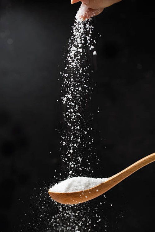 salt in wooden spoon on black background. - food stock pictures, royalty-free photos & images