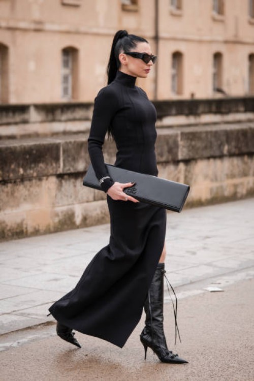 Sandra Corinna Kinzl wears black long turtleneck dress, black Balenciaga sunglasses, black Balenciaga bag, black boots, outside Balenciaga, during...