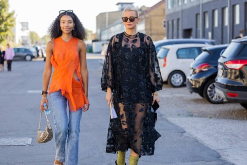 Sara Flaaen Licius wearing orange top, denim jeans & Andrea Steen wearing black sheer dress seen outside Henrik Vibskov during Copenhagen Fashion...