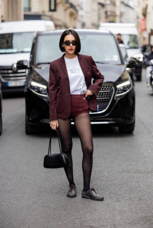 Sara Legge wears burgundy shorts, blazer, tights, black bag outside Lacoste during Womenswear Spring/Summer 2025 as part of Paris Fashion Week on...