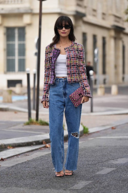 Sarah Ellen wears a colored checkered tweed jacket, a white tank top, blue ripped jeans, a Chanel clutch, outside Chanel, during the Womenswear...