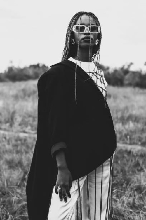 schwarz-weiß-fotografie. schöne frau in anzug und jacke im freien. authentischer stil. sommermode. model mit afro-frisur. stilvolle accessoires. ohrringe. - fashion stock-fotos und bilder