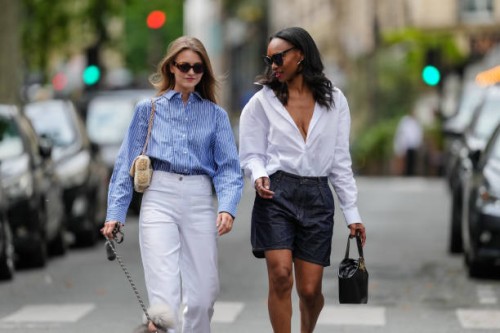 Segolene Hyppolite wears sunglasses, a blue and white oversized shirt from Tommy Hilfiger, a raffia beige bag from Vanessa Bruno, high waist white...