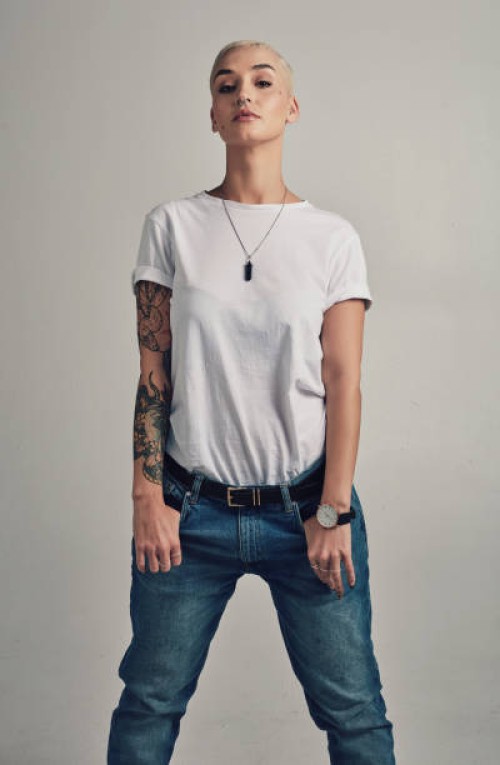selbstbewusstsein, denim und porträt einer frau mit tattoo-mode, kreativer kultur und jeans im studio. künstlerisches mädchen mit hipster-identität, trendigem stil und cooler kleidung mit stolz auf grauem hintergrund. - fashi