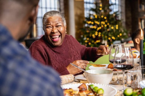 senior black woman laughing at dinner table on christmas day - home decoration stock pictures, royalty-free photos & images