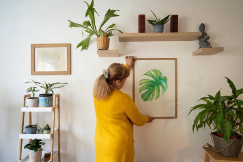 senior caucasian woman decorating her home with a new painting - home decoration stock pictures, royalty-free photos & images