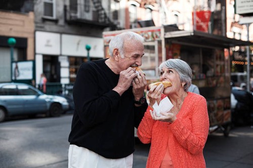 senior couple enjoying hot dogs on city street - junk food stock pictures, royalty-free photos & images