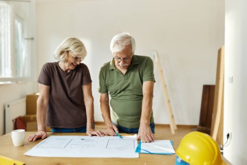 senior couple examining blueprints during home renovation process. - home decoration stock pictures, royalty-free photos & images