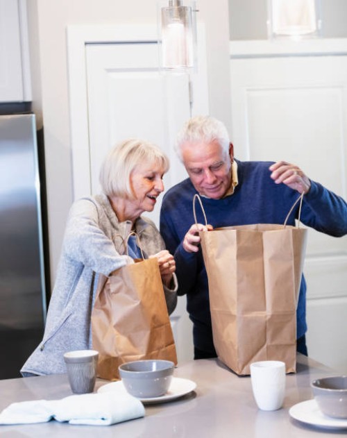 senior couple with bags of take out food in home kitchen - junk food stock pictures, royalty-free photos & images