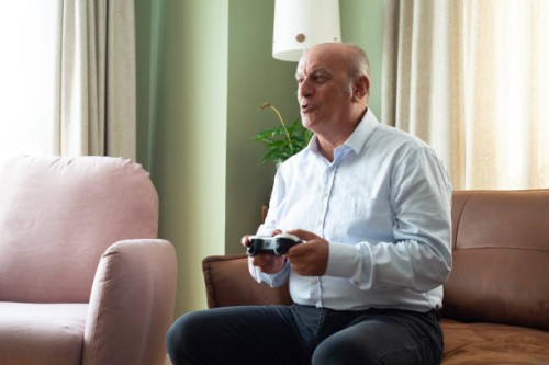 senior man enjoying video game on playstation, having fun at home - junk food stock pictures, royalty-free photos & images