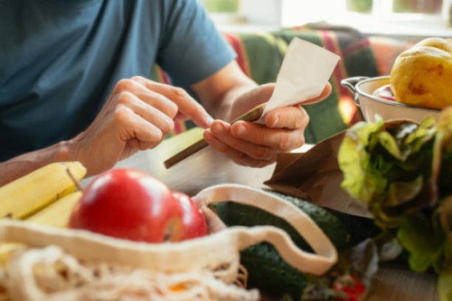 senior man unpacking groceries at kitchen and looking at receipts, financial crisis, environment conservation and sustainability concept - food stock pictures, royalty-free photos & images