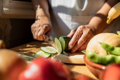 senior woman cutting cucumber in kitchen - food stock pictures, royalty-free photos & images