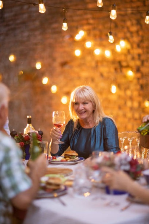senior woman enjoying fun time with her friends on dinner party at backyard - garden decoration stock pictures, royalty-free photos & images