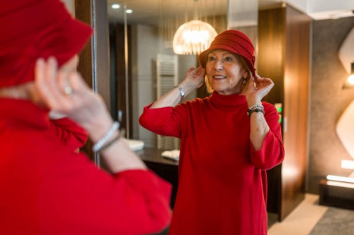 senior woman styling her hat in a mirror - fashion stock pictures, royalty-free photos & images