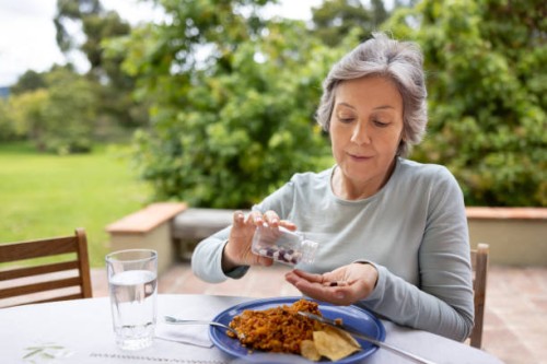 senior woman taking her medicines with food while eating lunch - food stock pictures, royalty-free photos & images