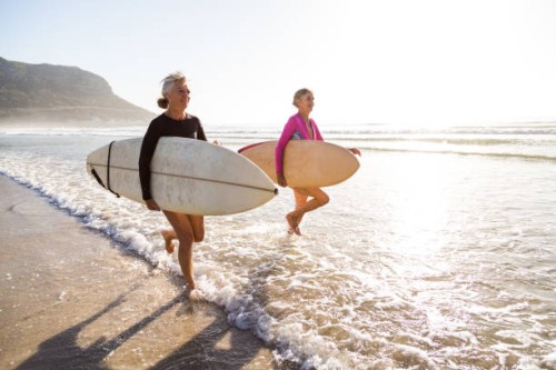 senior women going for a morning surf in the sea - travel stock pictures, royalty-free photos & images