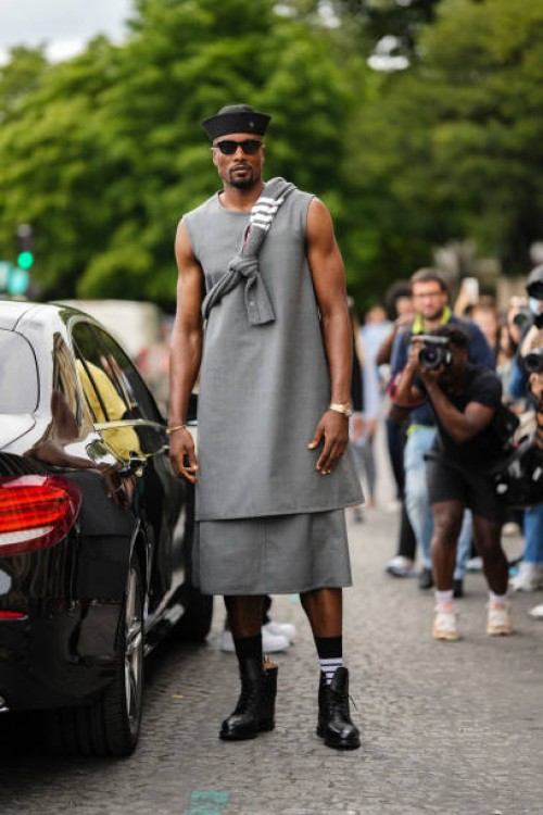 Serge Ibaka wears a black sailor's hat, black sunglasses, a gray with white striped print pattern wool pullover, a gray long / large tank-top, a...