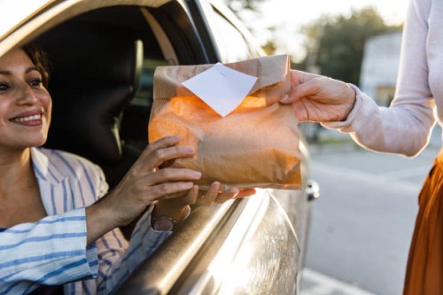 service person giving customer her order at the drive through - junk food stock pictures, royalty-free photos & images