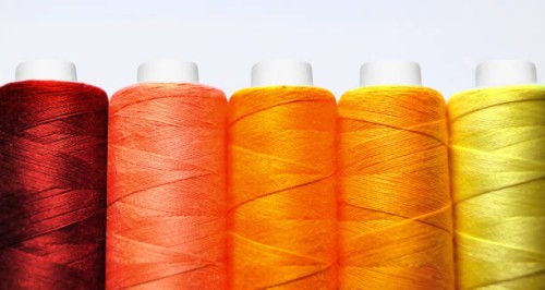 set of spools of red, yellow and orange threads front view close-up macro on white background - fashion stock pictures, royalty-free photos & images