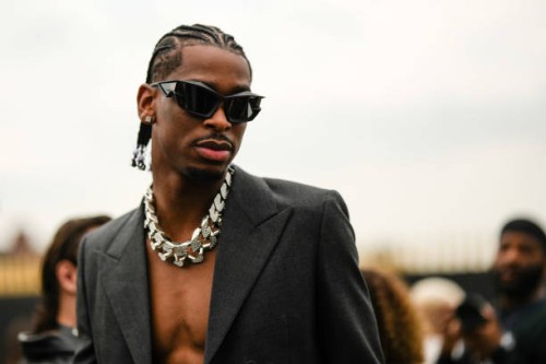 Shai Gilgeous-Alexander wears black sunglasses, a silver and diamonds, a dark gray blazer jacket, outside the Givenchy show, during Paris Fashion...
