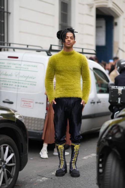 Sharl wears a yellow fluffy turtleneck pullover, leather pants, knee high leather boots with yellow shoelace, outside Marni, during the Womenswear...