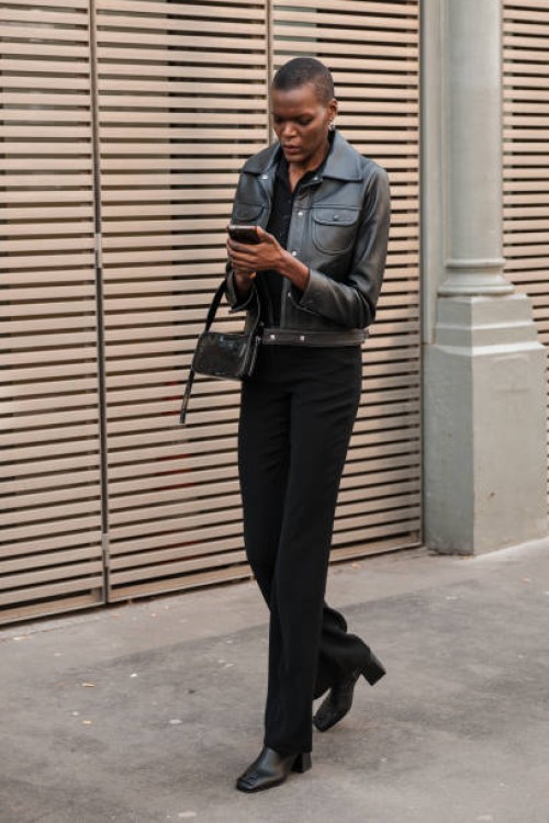 Sheila Atim wears black leather jacket, black trousers, black boots, black bag, outside Courreges, during the Womenswear Fall/Winter 2024/2025 as...