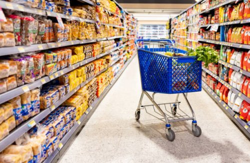 shopping cart in the aisle of a supermarket - junk food stock pictures, royalty-free photos & images