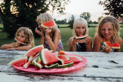 siblings having fun eating watermelon outside in summertime - garden decoration photos et images de collection