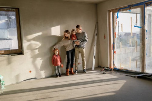 siblings with parents standing in front of wall at incomplete home - home decoration stockfoto's en -beelden