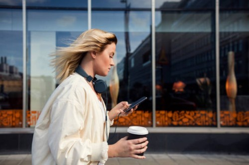 side view of woman using mobile phone while holding disposable cup against building - fashion stock pictures, royalty-free photos & images