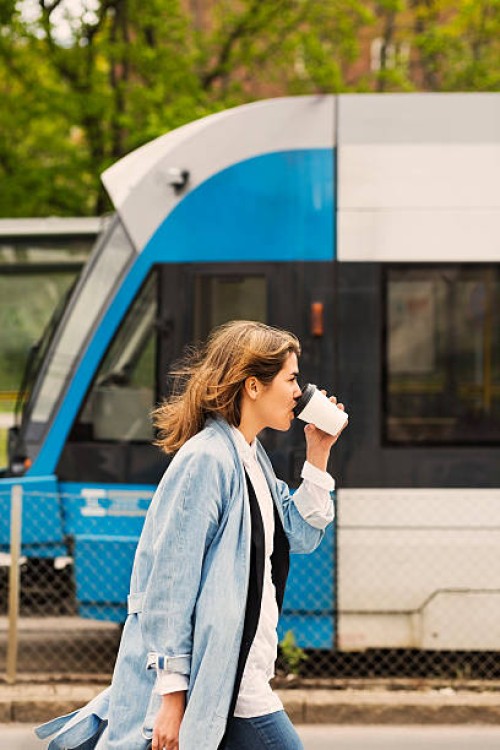 side view of young woman drinking coffee at tram station - junk food stock pictures, royalty-free photos & images