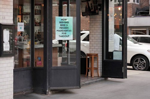 Sign in a restaurant window advertises beer and margaritas for takeout during the coronavirus pandemic on May 19, 2020 in New York City. COVID-19 has...