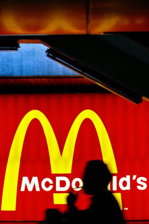 Silhouetted pedestrian lights up a cigarette as he walks past a fast food billboard for US chain McDonald's in Hong Kong, 07 March 2007. Hong Kong's...