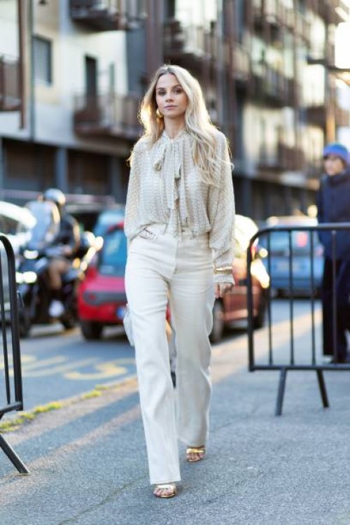 Simona Jakstaite wears gold heeled sandals, gold hoop earrings, a beige Missoni long sleeved shirt, gold bracelets, a white cream Bottega Veneta...