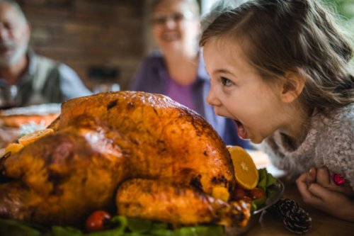 small girl having fun while about to bite a roasted turkey on thanksgiving. - food stock pictures, royalty-free photos & images