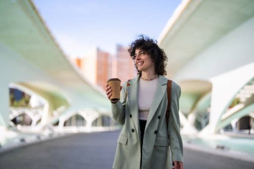 smart young female student looking away while holding coffee to go. - junk food stock pictures, royalty-free photos & images