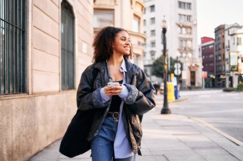 smiley afro woman using a mobile walking in the street - fashion stock pictures, royalty-free photos & images