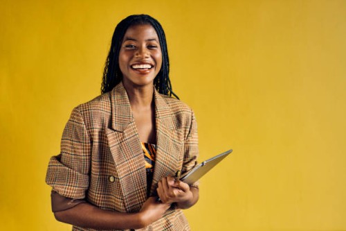 smiling african american businesswoman in a plaid blazer holding a tablet in a modern office. empowerment and professional growth in business concept - home decoration stock-fotos und bilder