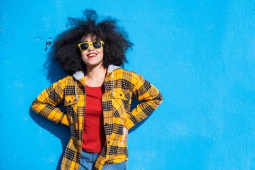 smiling american-african woman standing on a blue background - fashion stock pictures, royalty-free photos & images