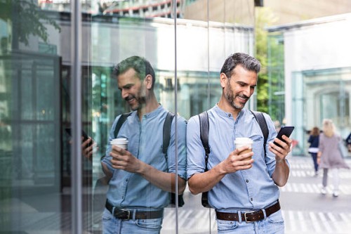 smiling businessman looking at the smartphone in the city, berlin, germany - junk food stock pictures, royalty-free photos & images