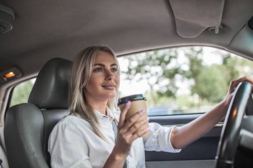 smiling businesswoman holding takeaway coffee driving car - junk food stock pictures, royalty-free photos & images