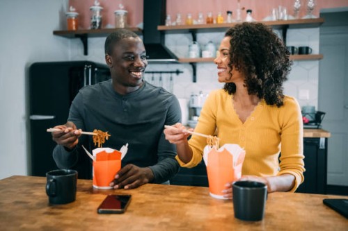 smiling couple having lunch together at home. - junk food stock pictures, royalty-free photos & images